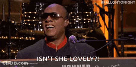 A Man Is Singing Into A Microphone While Sitting At A Keyboard . GIF