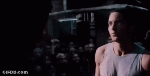 A Man Is Singing Into A Microphone While Standing In A Boxing Ring . GIF