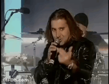 A Man Is Singing Into A Microphone While Standing On A Stage . GIF