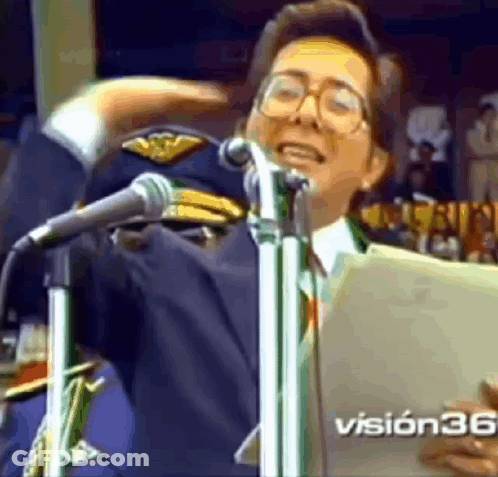 A Man Is Singing Into A Microphone While Wearing A Military Hat And Glasses . GIF