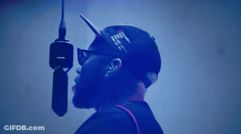 A Man Is Singing Into A Microphone With A Hat That Says ' I Love You ' On It GIF