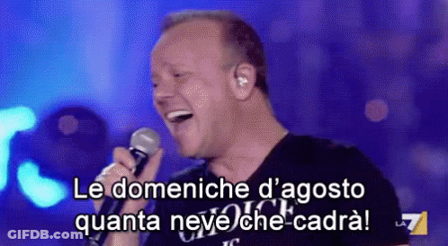 A Man Is Singing Into A Microphone With The Words Le Domeniche D' Agosto Quanta Neve Che-Cadra GIF