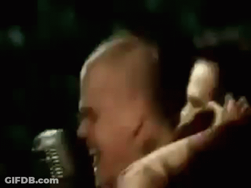 A Man Is Singing Into A Microphone With The Words `` Scotty Doesn T Know '' Written On His Head . GIF