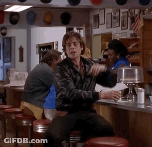 A Man Is Sitting At A Counter In A Diner Holding A Cup Of Coffee . GIF