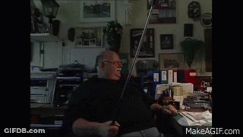 A Man Is Sitting At A Desk In A Room With A Makeagif.com Watermark In The Corner GIF