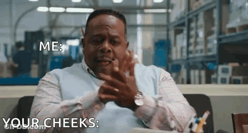 A Man Is Sitting At A Desk In A Warehouse Making A Funny Face While Talking To Someone . GIF