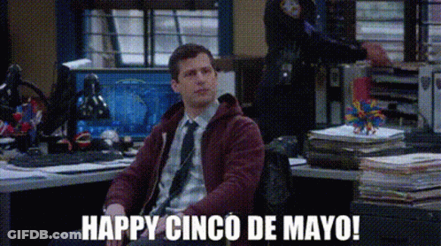 A Man Is Sitting At A Desk In An Office With The Words `` Happy Cinco De Mayo '' Written On The Screen . GIF