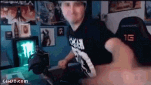 A Man Is Sitting At A Desk In Front Of A Computer In A Room . GIF