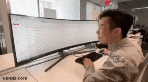 A Man Is Sitting At A Desk In Front Of A Computer Monitor And Keyboard . GIF
