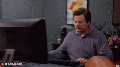 A Man Is Sitting At A Desk In Front Of A Computer Monitor . GIF