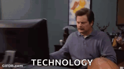 A Man Is Sitting At A Desk In Front Of A Computer With The Word Technology On The Screen . GIF