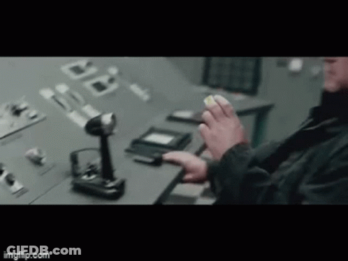 A Man Is Sitting At A Desk In Front Of A Control Panel . GIF