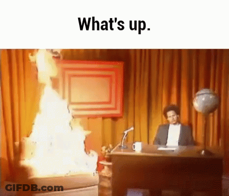 A Man Is Sitting At A Desk In Front Of A Fire And The Words What 'S Up . GIF