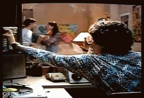 A Man Is Sitting At A Desk Looking At A Tv Screen GIF
