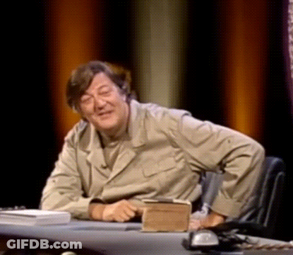 A Man Is Sitting At A Desk With A Book And A Phone On It . GIF