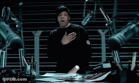A Man Is Sitting At A Desk With A Bunch Of Microphones . GIF