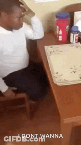 A Man Is Sitting At A Desk With A Plate On It And A Bottle Of Water . GIF