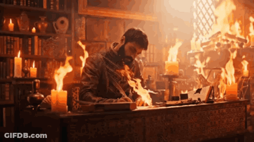 A Man Is Sitting At A Desk With Flames Coming Out Of It GIF