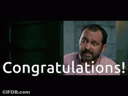A Man Is Sitting At A Desk With The Words Congratulations Written On The Screen GIF