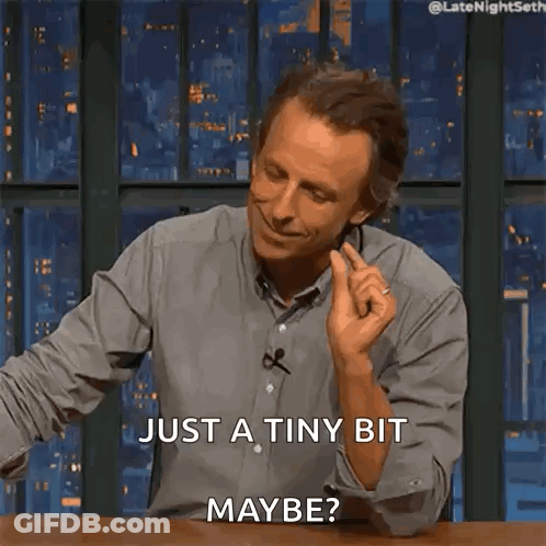 A Man Is Sitting At A Table And Smiling And Says Just A Tiny Bit Maybe GIF