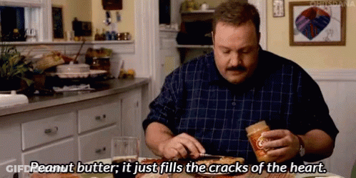 A Man Is Sitting At A Table Eating A Pizza With Peanut Butter On It . GIF