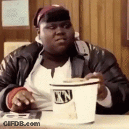 A Man Is Sitting At A Table Holding A Cup That Says ' Nn ' On It GIF