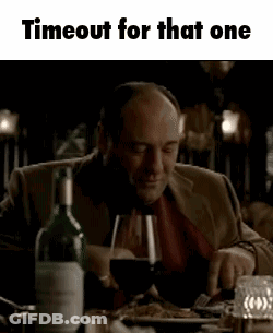 A Man Is Sitting At A Table Holding A Glass Of Wine . GIF