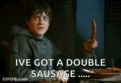 A Man Is Sitting At A Table Holding A Sausage And Saying `` Ive Got A Double Sausage '' . GIF