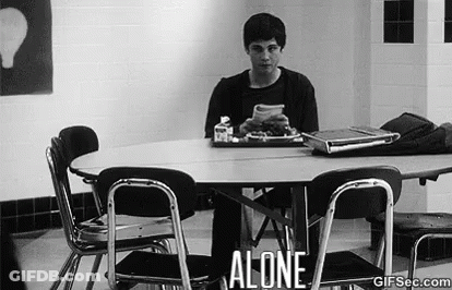 A Man Is Sitting At A Table In A Cafeteria Alone . GIF