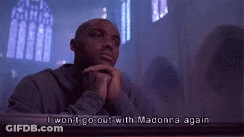 A Man Is Sitting At A Table In A Church With His Hands Folded . GIF