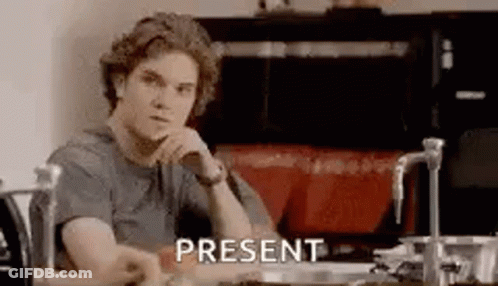 A Man Is Sitting At A Table In A Kitchen With His Hand On His Chin And The Word Present . GIF