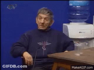 A Man Is Sitting At A Table In Front Of A Water Dispenser GIF
