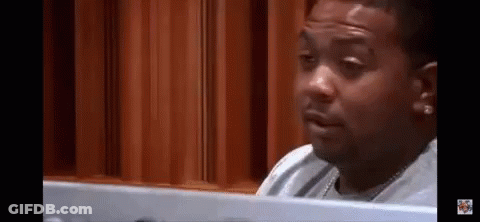 A Man Is Sitting At A Table Looking At A Computer Screen And Making A Funny Face . GIF