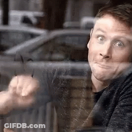 A Man Is Sitting At A Table Looking Out Of A Window . GIF
