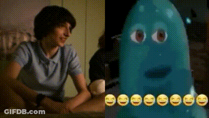 A Man Is Sitting At A Table Next To A Blue Ghost With Smiley Faces On Its Face . GIF