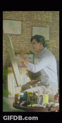 A Man Is Sitting At A Table Painting On An Easel And The Words Voi Ai Are On The Bottom GIF