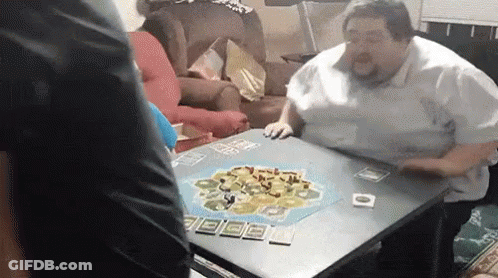A Man Is Sitting At A Table Playing A Game . GIF