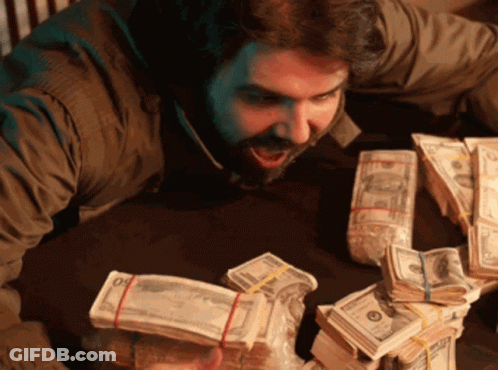 A Man Is Sitting At A Table Surrounded By Stacks Of Money Including A Stack Of 20 Bills GIF