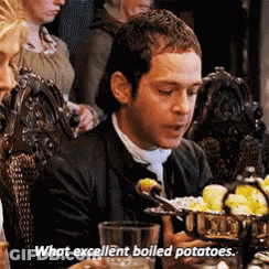 A Man Is Sitting At A Table With A Bowl Of Boiled Potatoes In Front Of Him . GIF