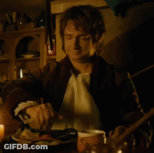 A Man Is Sitting At A Table With A Bowl Of Food And A Spoon GIF