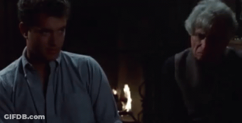 A Man Is Sitting At A Table With A Bowl Of Pretzels In Front Of Him GIF