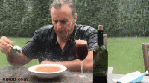 A Man Is Sitting At A Table With A Bowl Of Soup And A Bottle Of Wine .. GIF