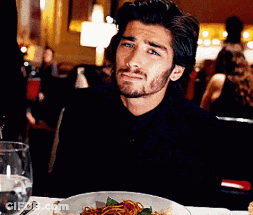 A Man Is Sitting At A Table With A Bowl Of Spaghetti On It GIF
