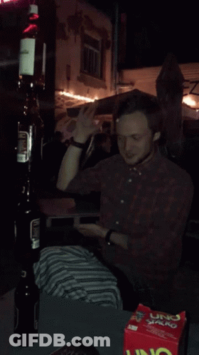 A Man Is Sitting At A Table With A Box Of Uno Chips GIF