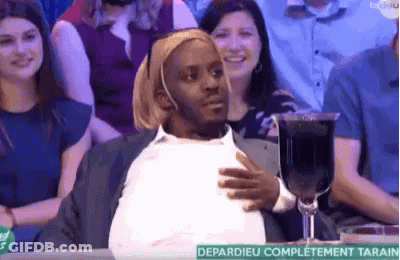 A Man Is Sitting At A Table With A Glass Of Wine . GIF