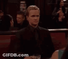 A Man Is Sitting At A Table With A Glass Of Wine And A Plate Of Food . GIF