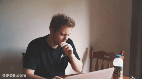A Man Is Sitting At A Table With A Laptop And A Bottle Of Water GIF