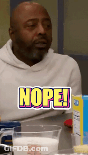 A Man Is Sitting At A Table With A Measuring Cup Of Milk And A Sticker That Says Nope GIF