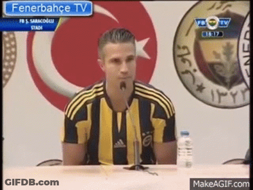 A Man Is Sitting At A Table With A Microphone In Front Of Him . GIF