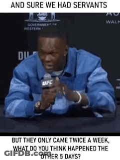 A Man Is Sitting At A Table With A Microphone In His Hand And Talking Into It . GIF